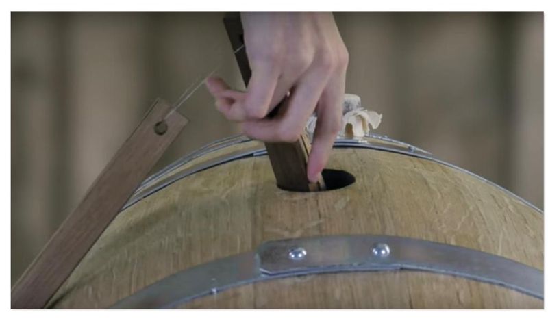 French oak insert sticks going into a wine barrel through the bung hole